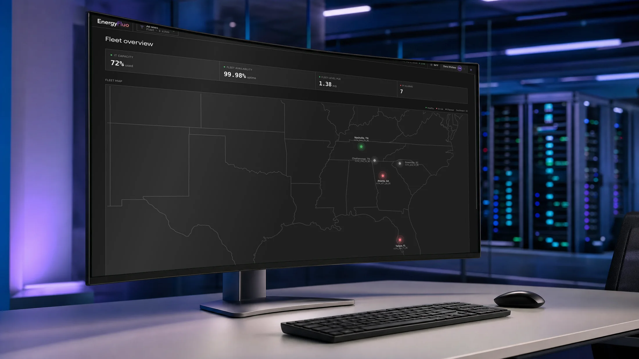 EnergyFluo fleet overview on a curved monitor: a map of sites with capacity, availability, efficiency and priority alarm indicators